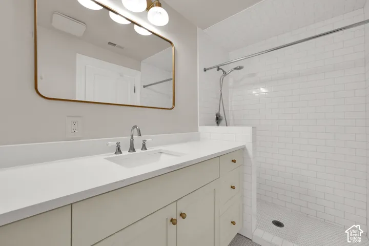 White subway tile shower enclosure with a mosaic tile floor, an integrated shower system, and a half-wall partition