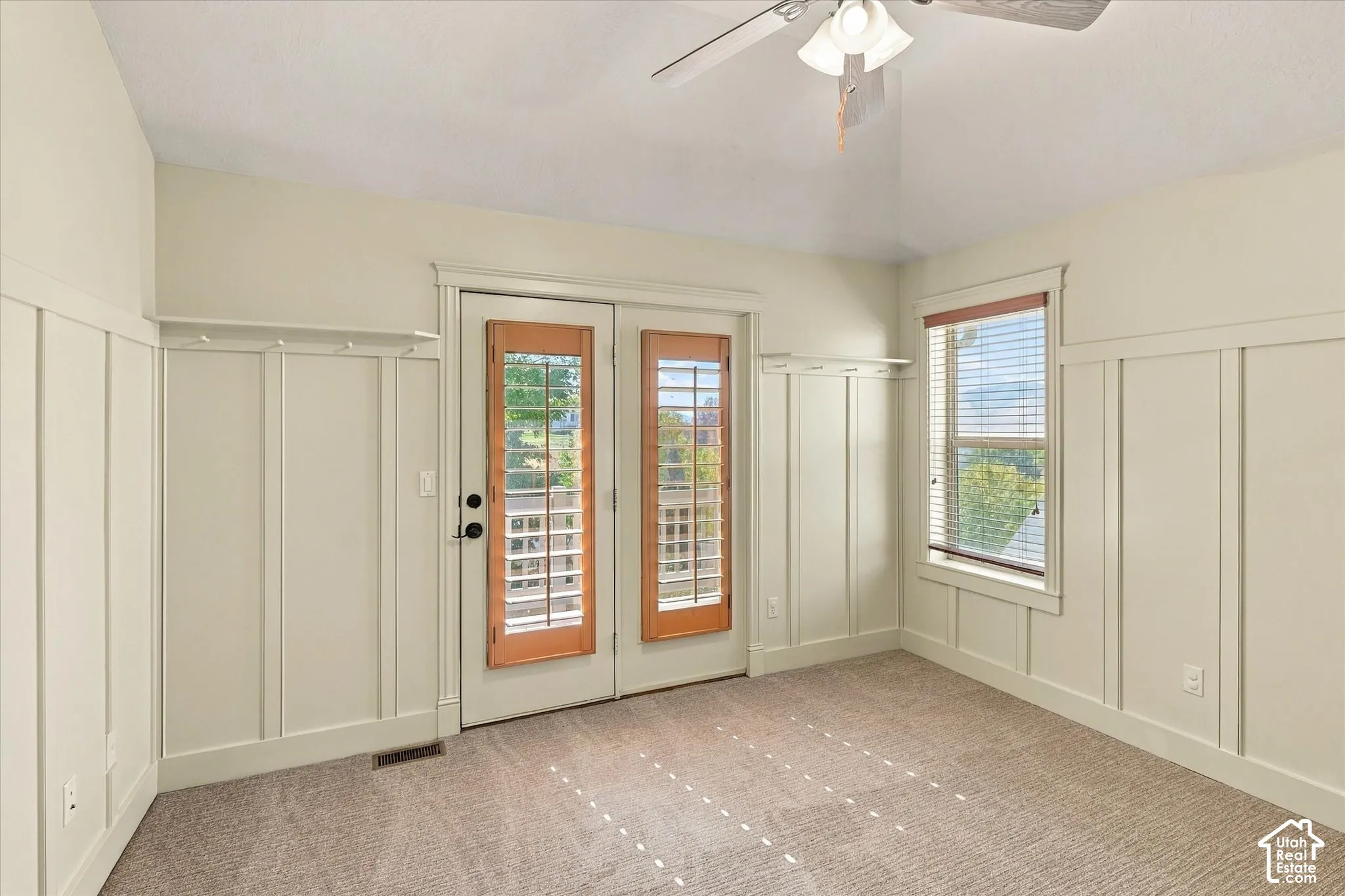 Board and batten wall detailing, double glass-paneled doors, integrated coat rack, window with wood blinds, and carpeted flooring