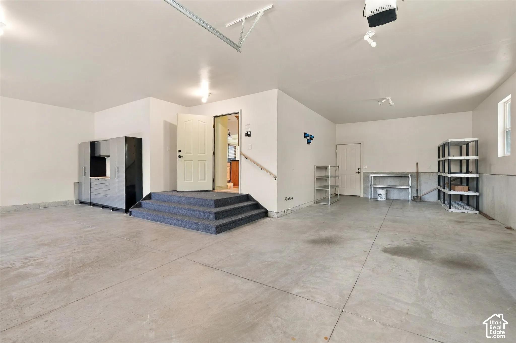 Spacious garage featuring concrete flooring, white painted walls, and built-in storage cabinetry