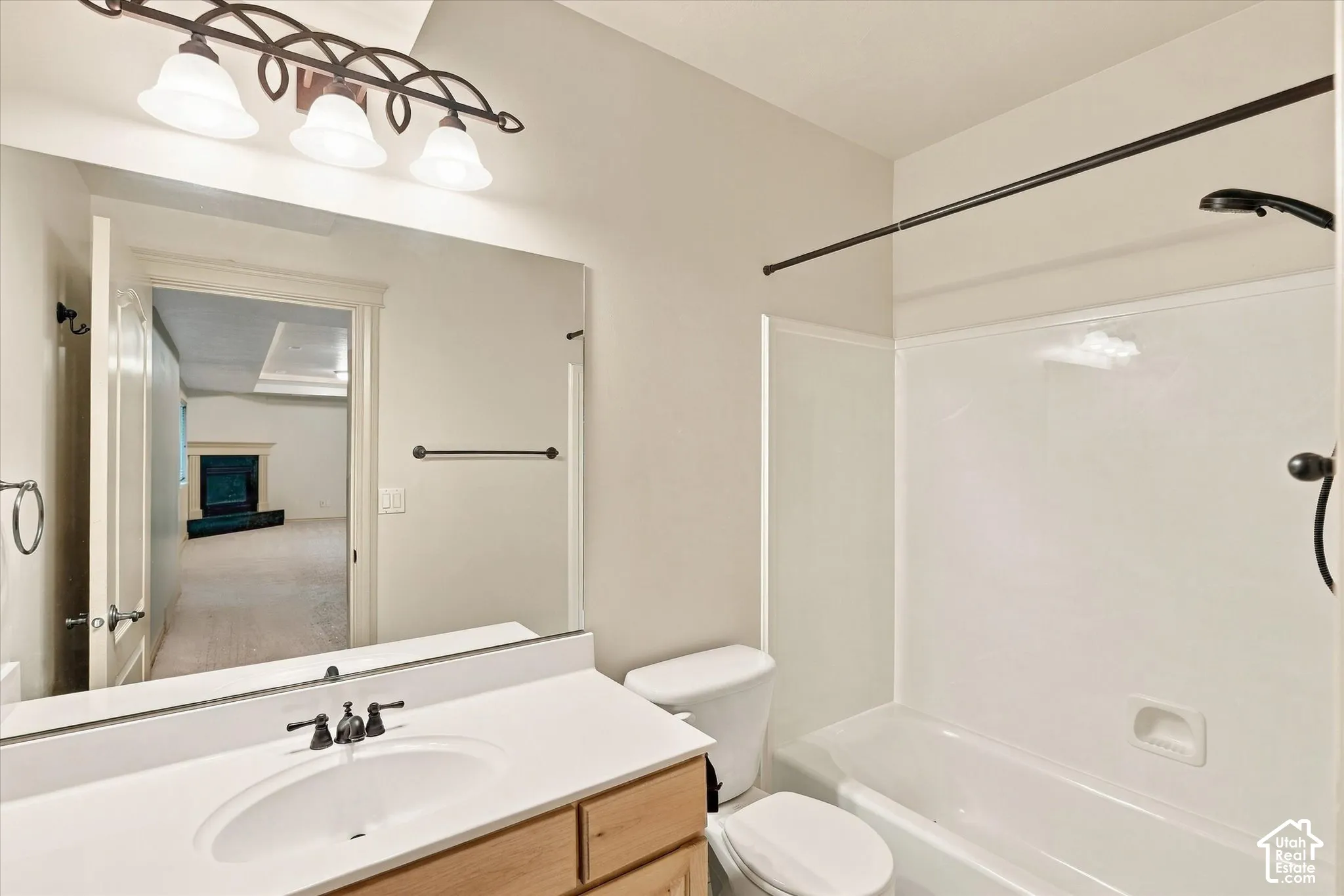 Vanity with an integrated sink, dark bronze fixtures, a three-light vanity bar, a toilet, and a shower-over-tub combination