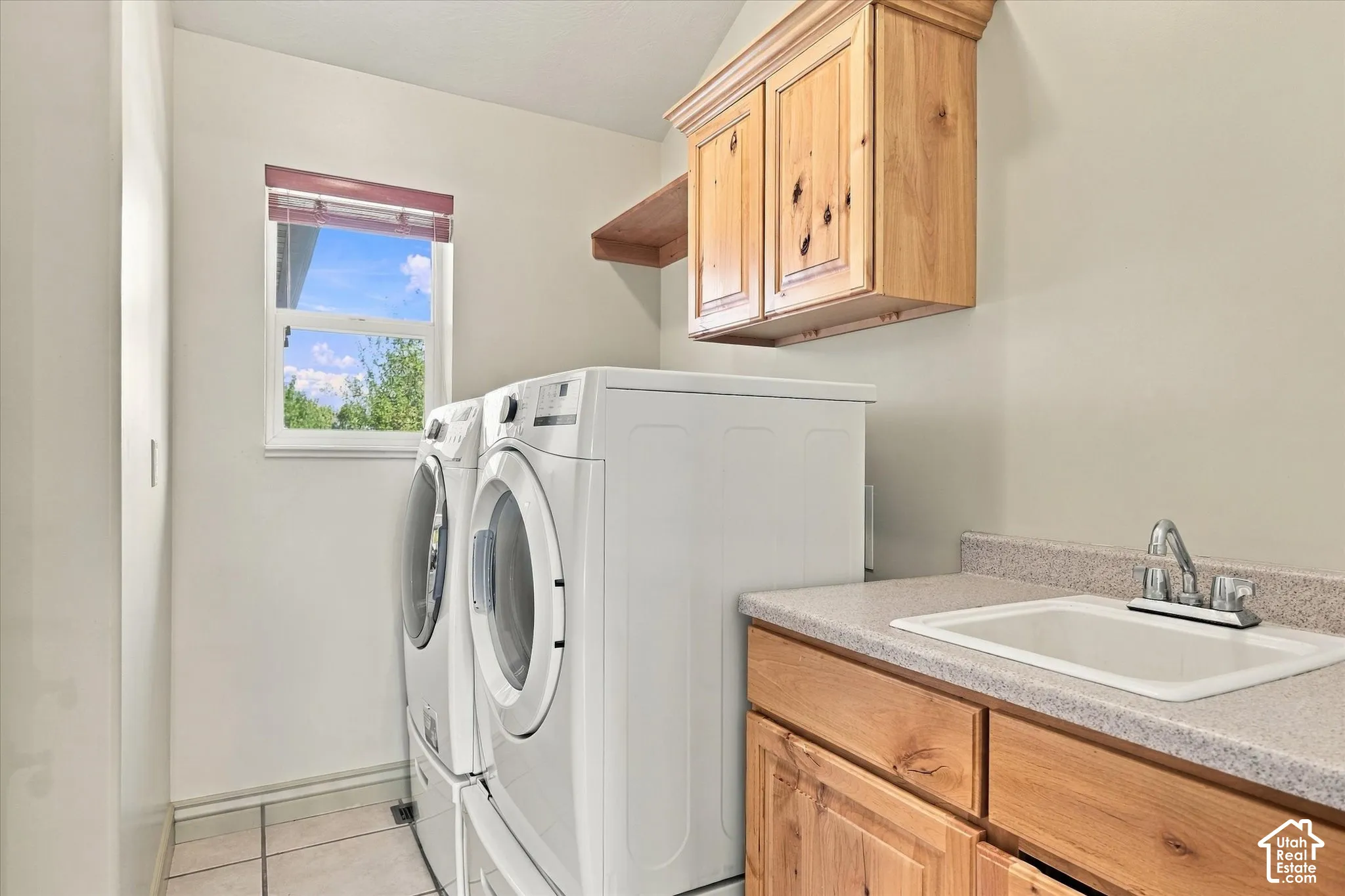 Laundry area featuring a window, wood-finish cabinetry, a utility sink, and a countertop