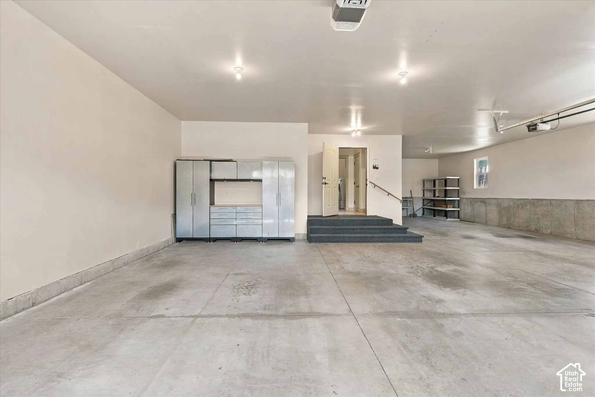 Spacious garage featuring concrete flooring, built-in storage cabinetry, overhead lighting, and interior access