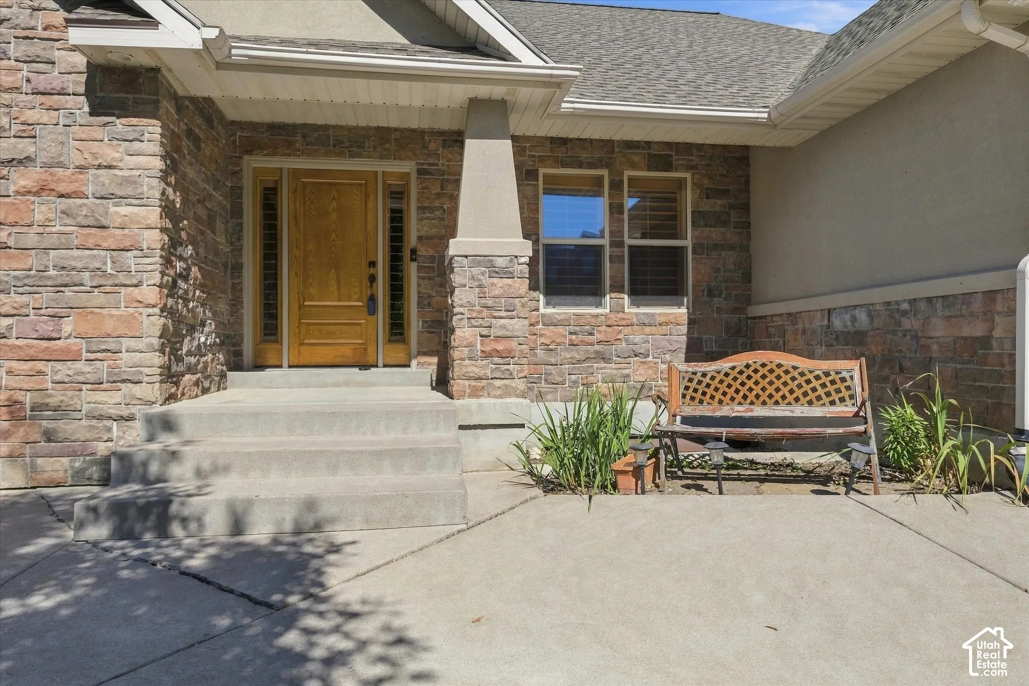 Stone veneer exterior with a wood-panel entry door, transom windows, and a covered porch