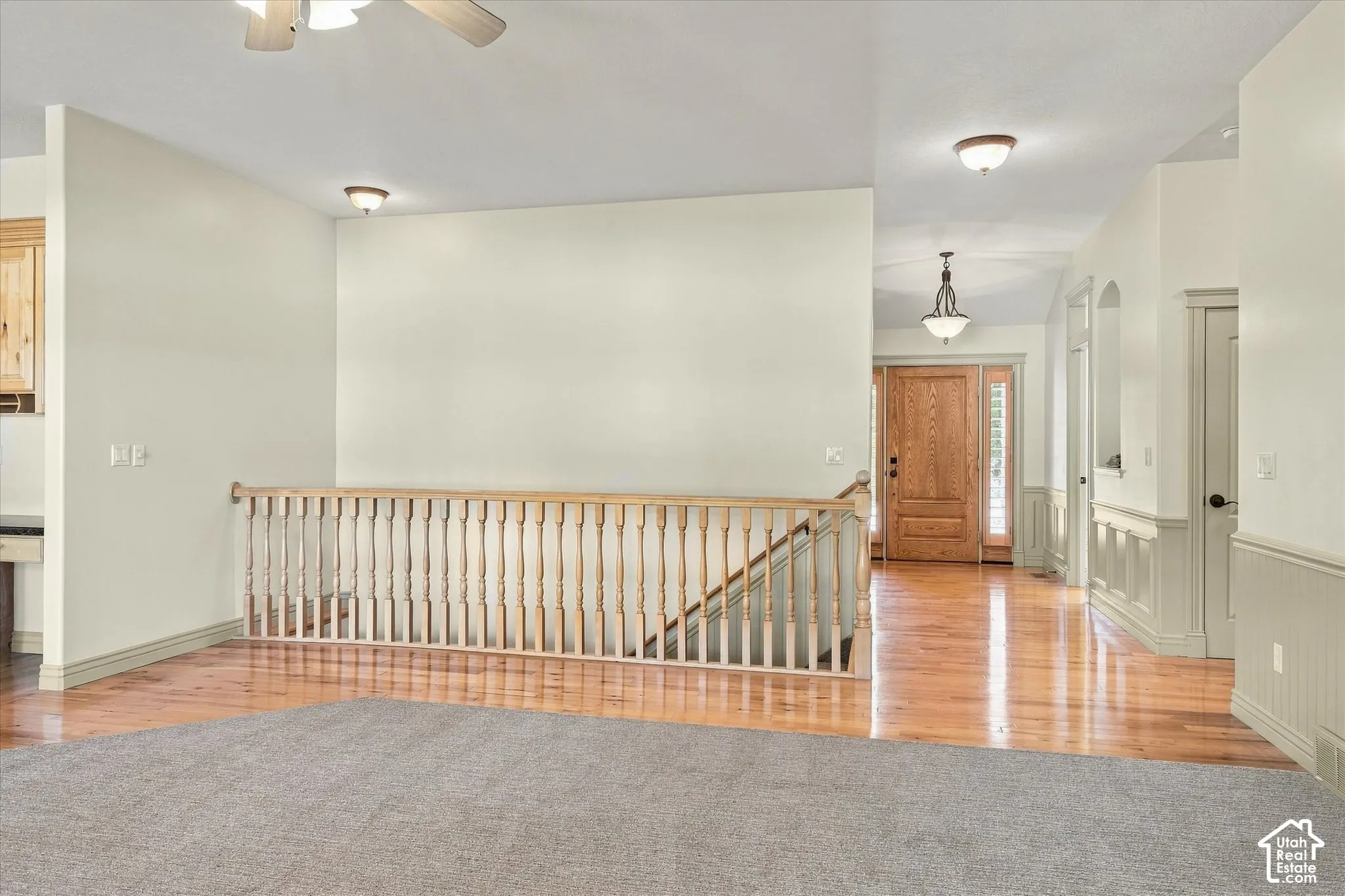 Wood-finish flooring, staircase with wood railing, recessed lighting, ceiling fan, and paneled entry door