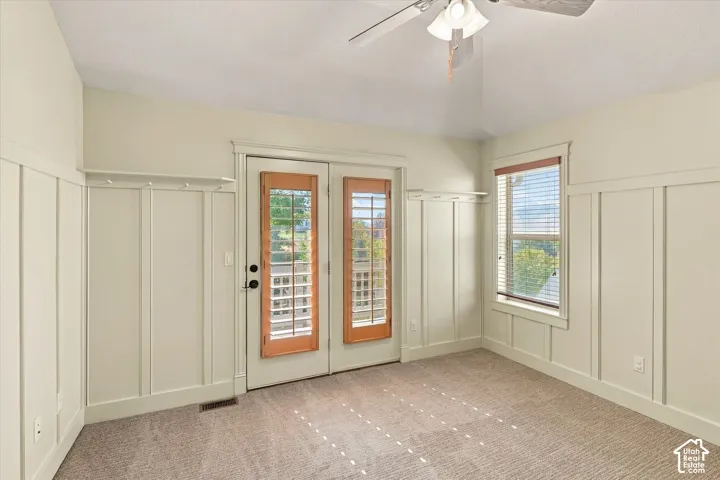 Board and batten wall detailing, double glass-paneled doors, integrated coat rack, window with wood blinds, and carpeted flooring