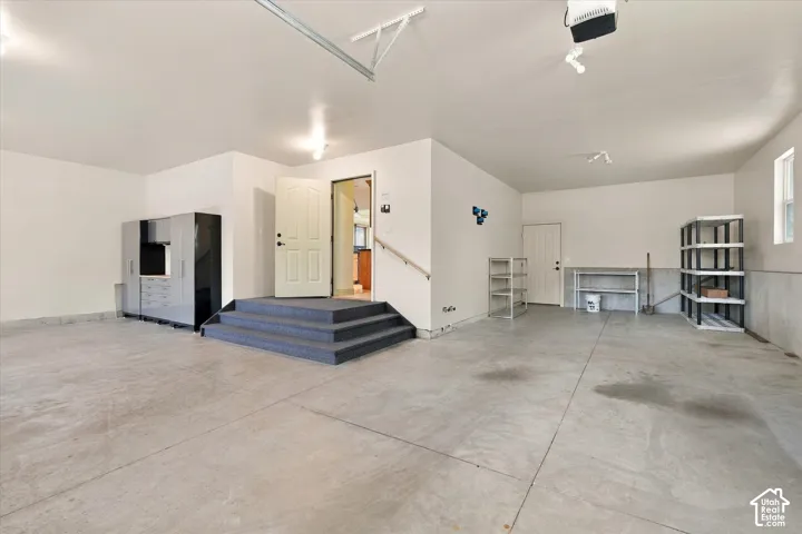 Spacious garage featuring concrete flooring, white painted walls, and built-in storage cabinetry