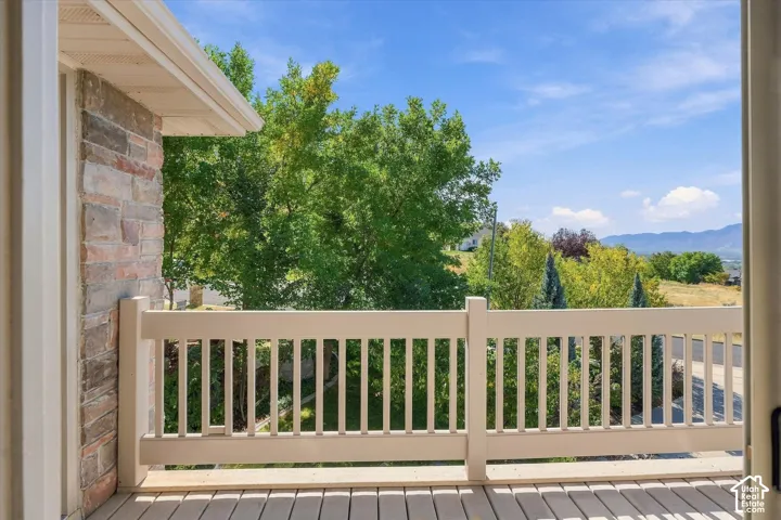 Stone exterior accent, composite deck flooring, white railing, mature trees, and distant mountains