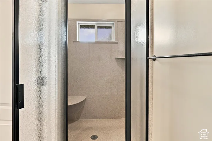 Shower enclosure with a privacy glass door, integrated bench, built-in shelving, and a horizontal window