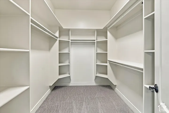 Walk-in closet with integrated shelving, multiple hanging rods, corner shelving, and carpeted flooring