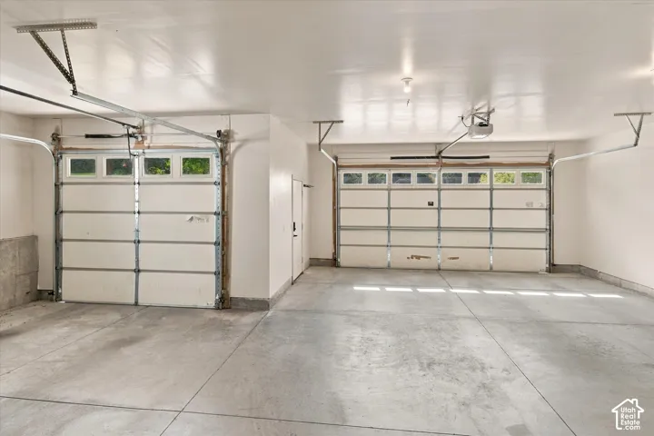 Two-car garage with concrete flooring, two overhead garage doors with window panels, and interior access door