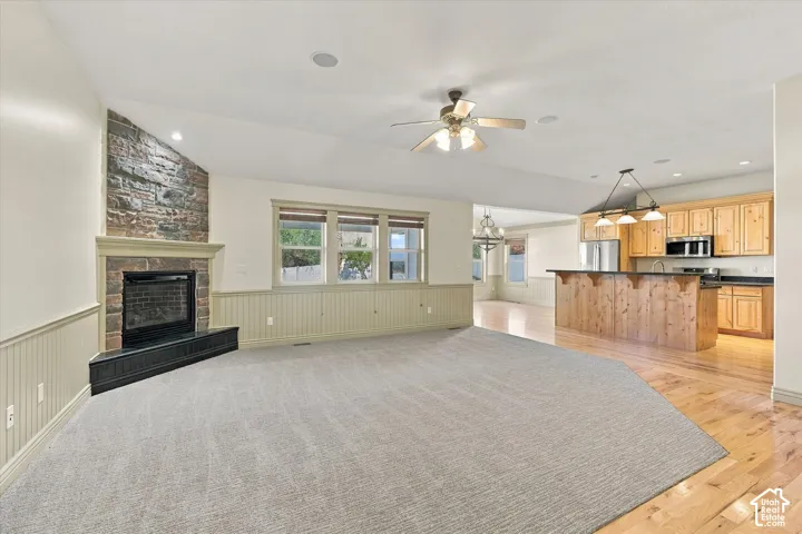 Stone-faced fireplace with a hearth, wood-finish flooring, recessed lighting, and a ceiling fan