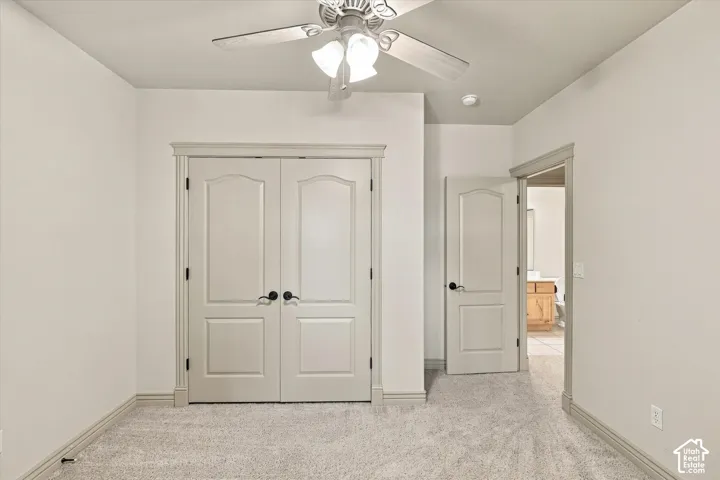 Textured carpeting, ceiling fan with light fixture, double panel doors, painted trim, and a single panel door