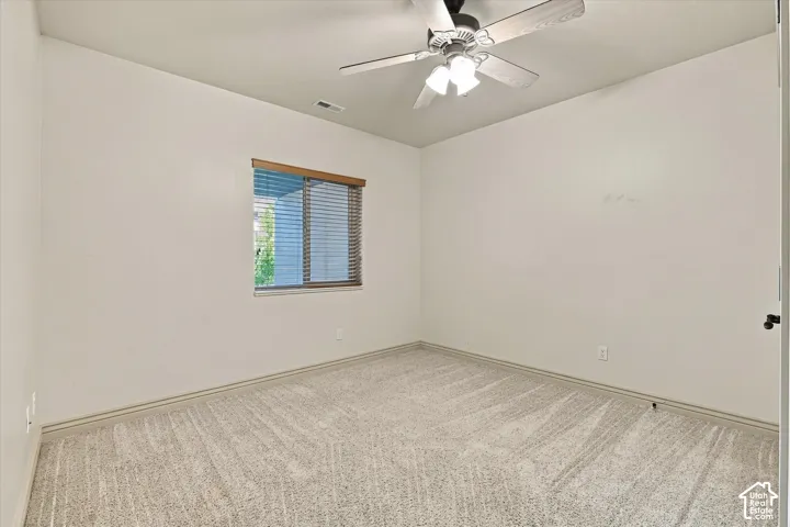 Wall-to-wall carpeting, window with wood-finish blinds, and a ceiling fan with integrated lighting