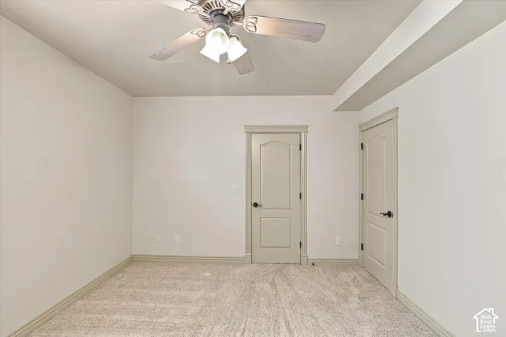 Neutral tone walls, ceiling fan with integrated lighting, two panel interior doors, and neutral carpet flooring