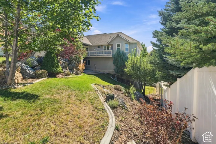Terraced backyard with mature trees, established landscaping, and a white privacy fence
