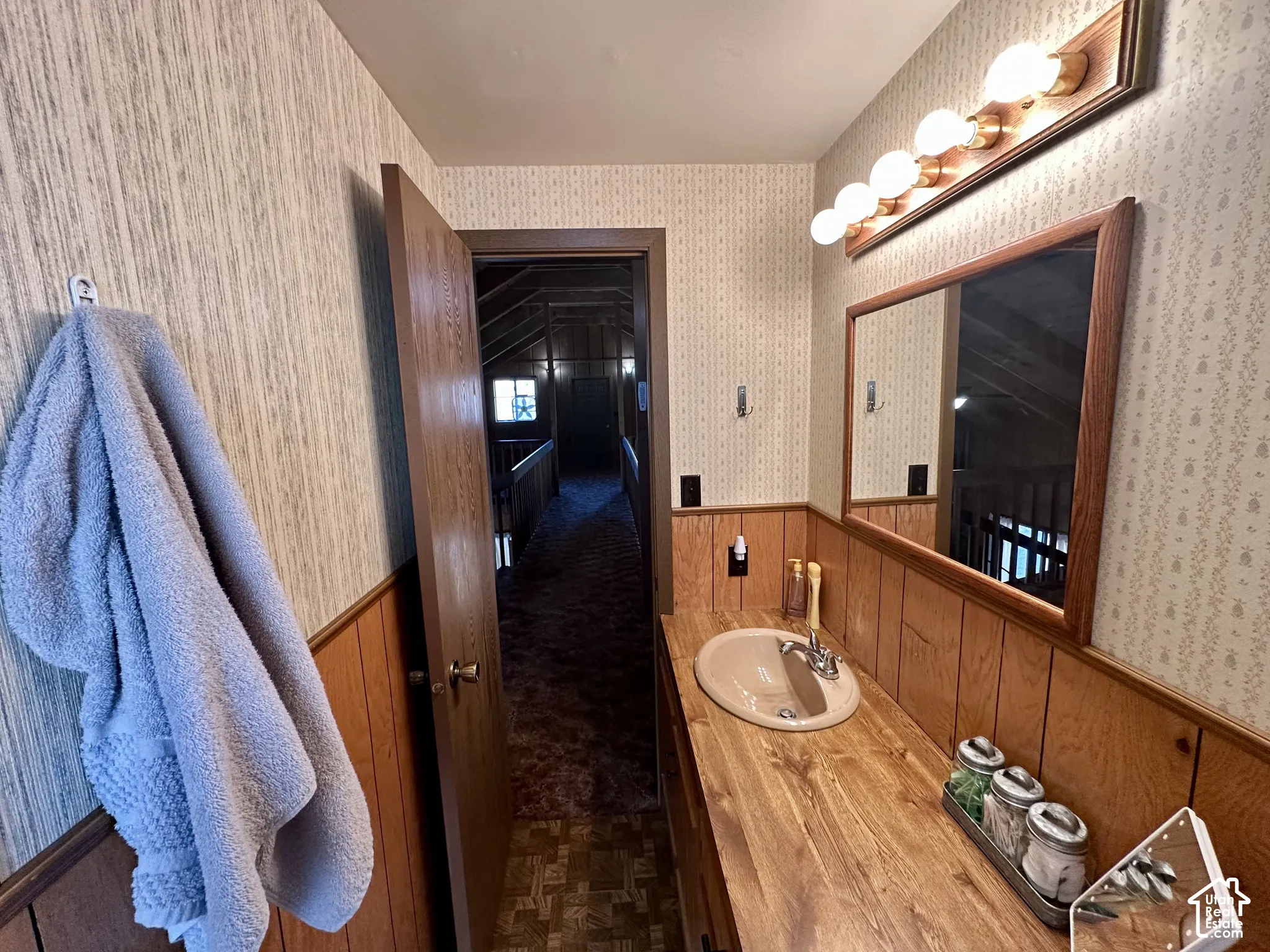 Vanity with integrated sink, wood-finish countertop, and wood-paneled accents
