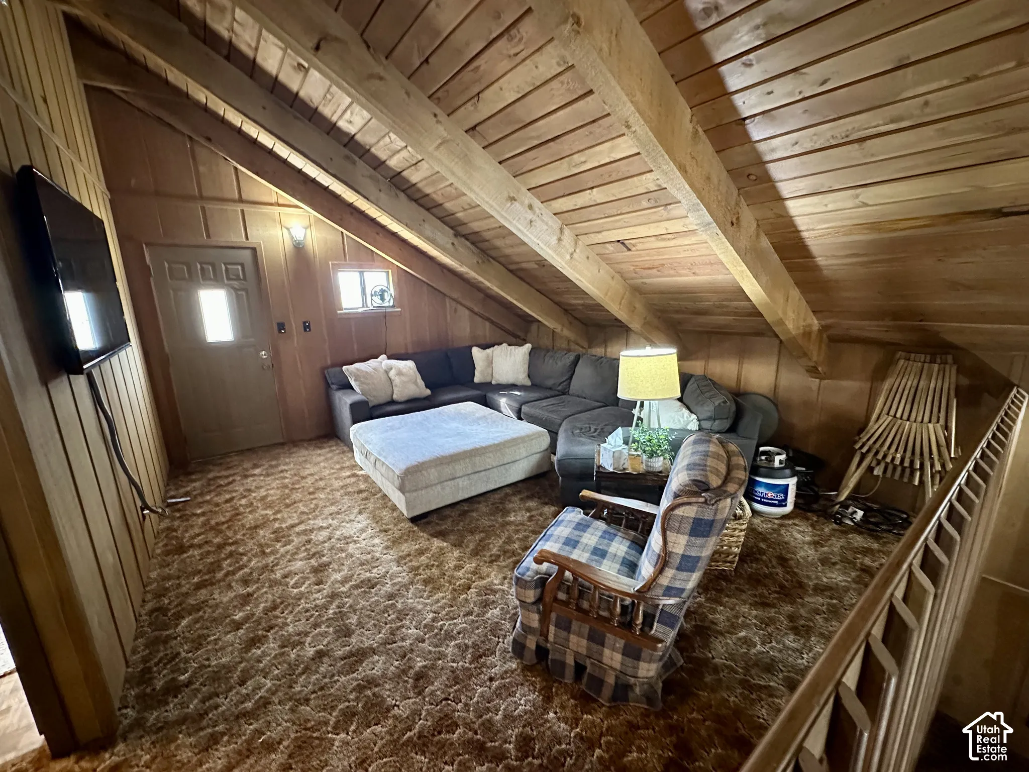 Vaulted wood-paneled ceiling with exposed beams, wood-paneled walls, and a multi-paneled door