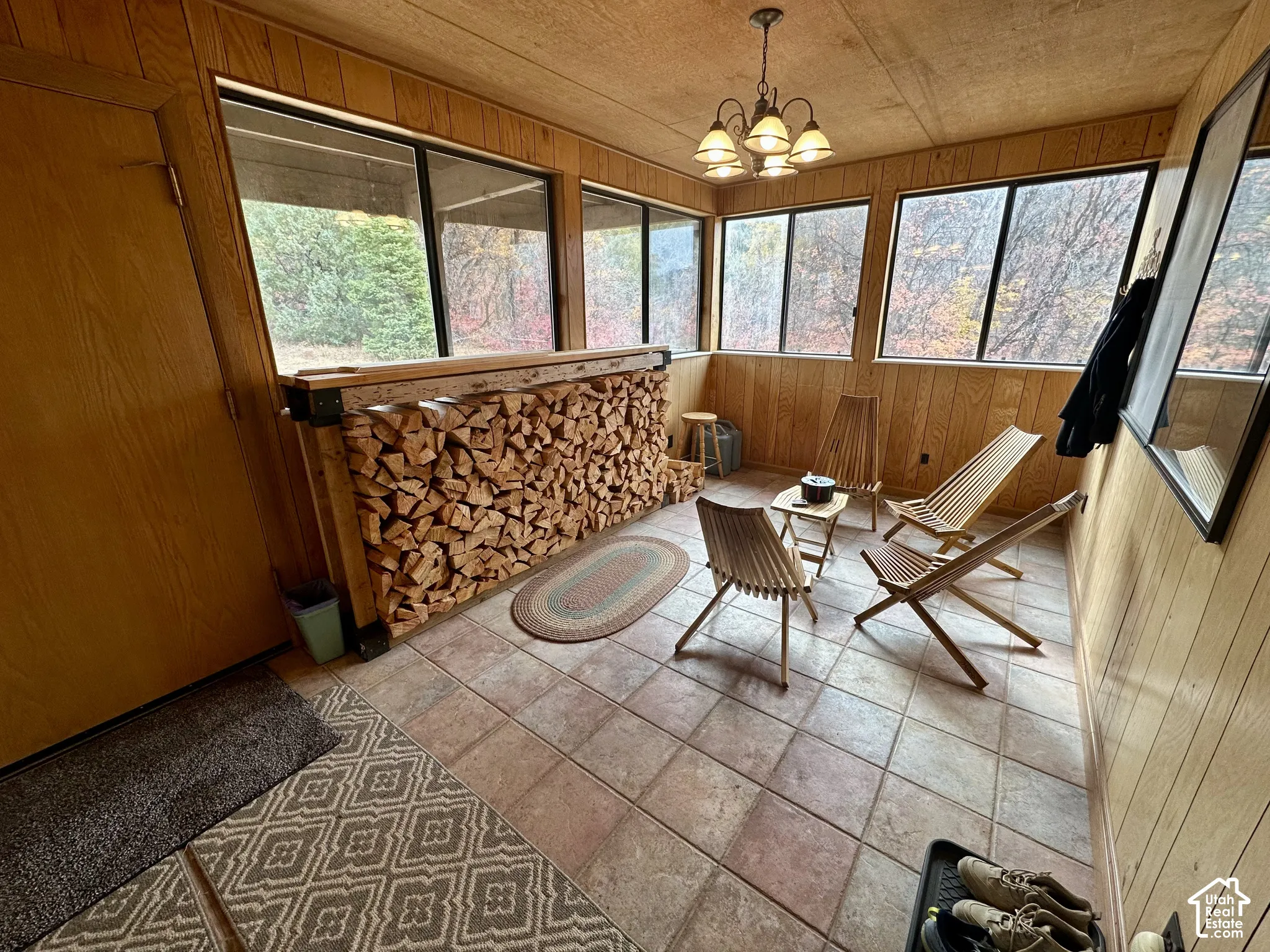 Wood paneling, tiled flooring, chandelier lighting fixture, multiple windows, built-in wood storage