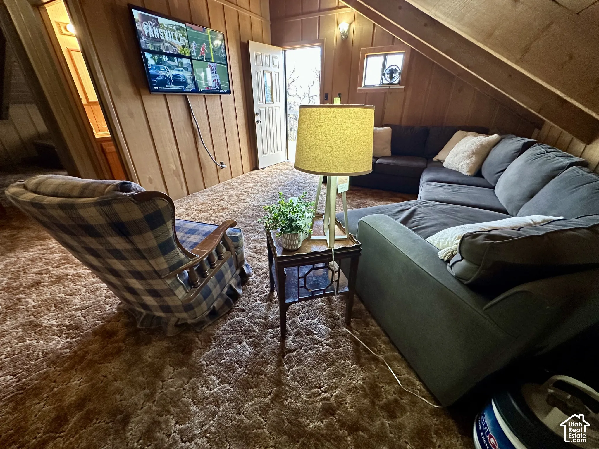 Vaulted wood-paneled ceilings with exposed beams, wall-mounted television, and a window for natural light