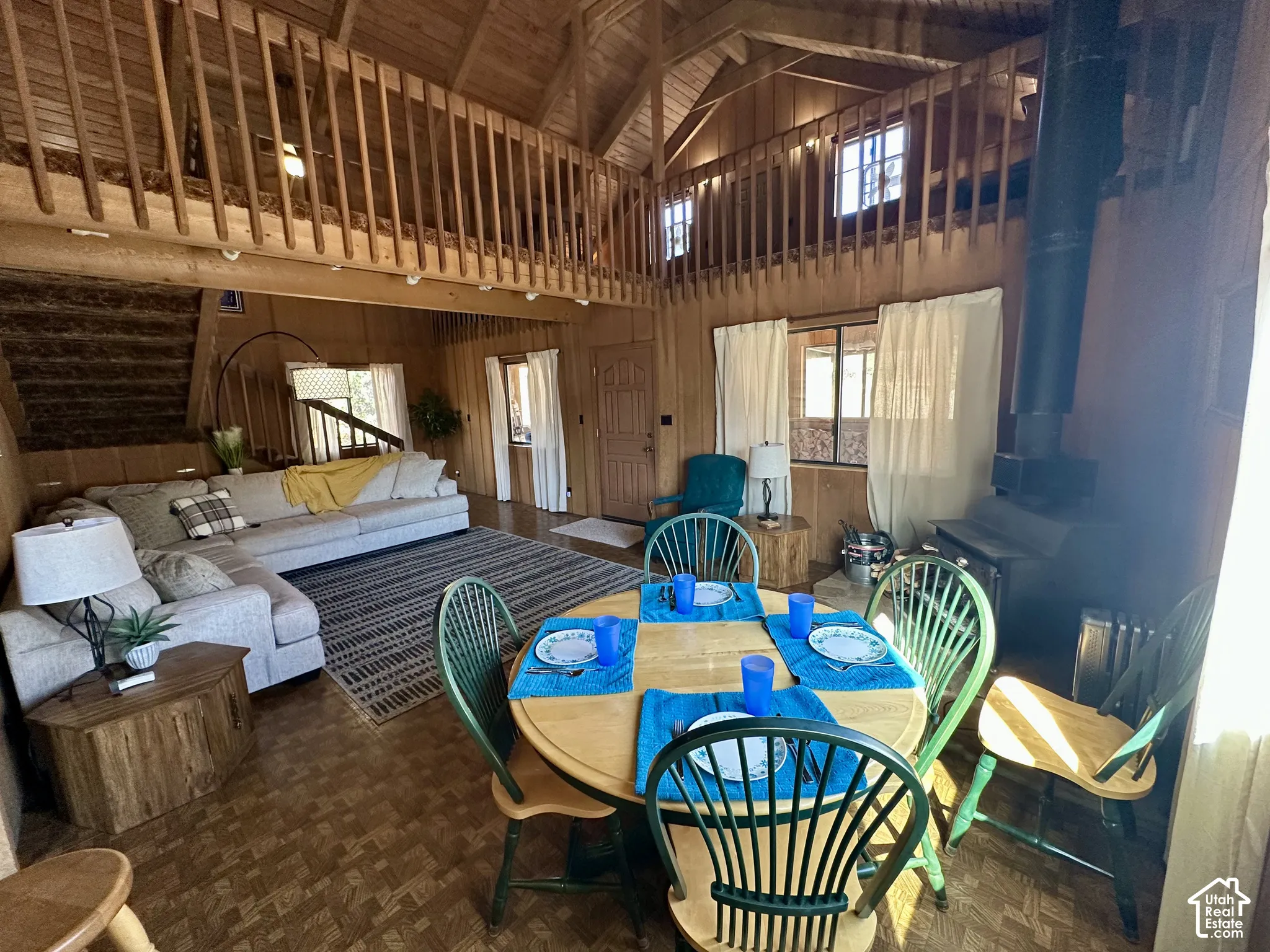 Vaulted wood-paneled ceilings with exposed beams, wood-finish flooring, and a second-story loft with wood railing