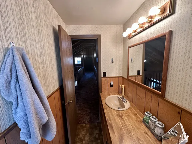 Vanity with integrated sink, wood-finish countertop, and wood-paneled accents