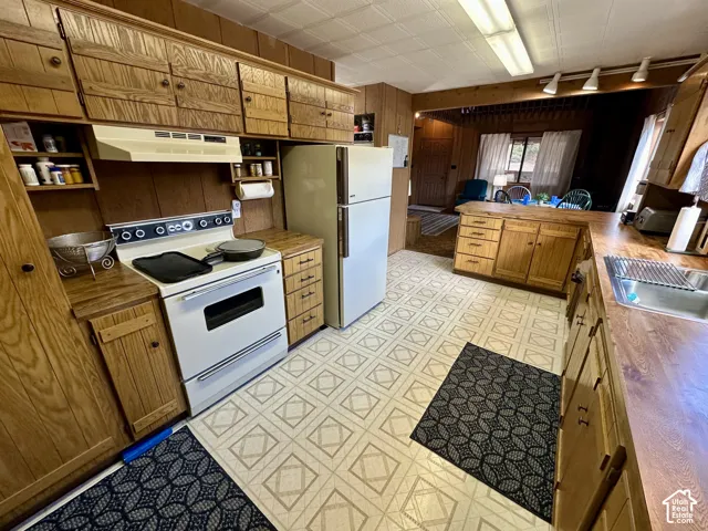 Wood-finish cabinetry, patterned vinyl flooring, and wood-finish countertops