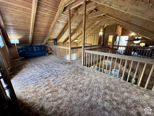 Vaulted wood-paneled ceilings with exposed beams, wood-finish railings, and a carpeted loft area