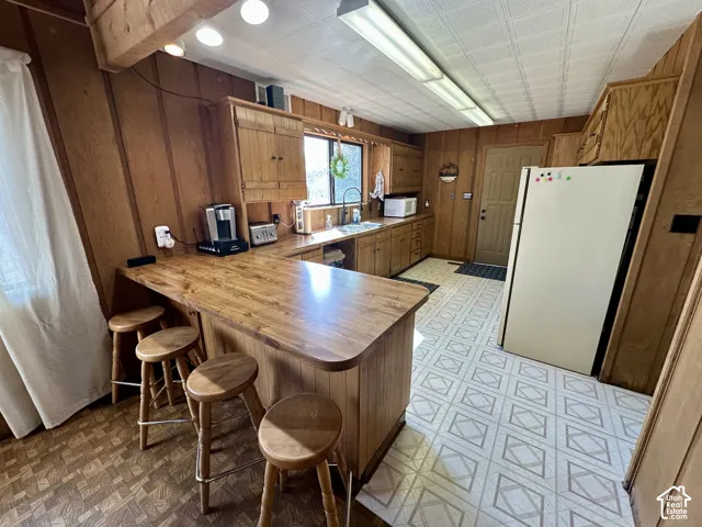 Wood-paneled walls with built-in cabinetry, wood-finish countertop, and integrated sink