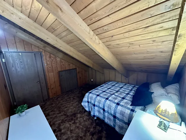 Vaulted wood-paneled ceiling with exposed beams, wood-paneled walls, and built-in doors