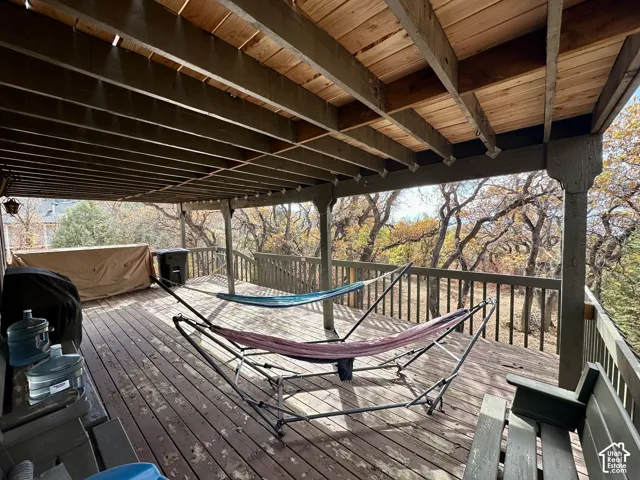 Expansive outdoor deck with wood-finish flooring, a wood railing, and an overhead wood beam structure