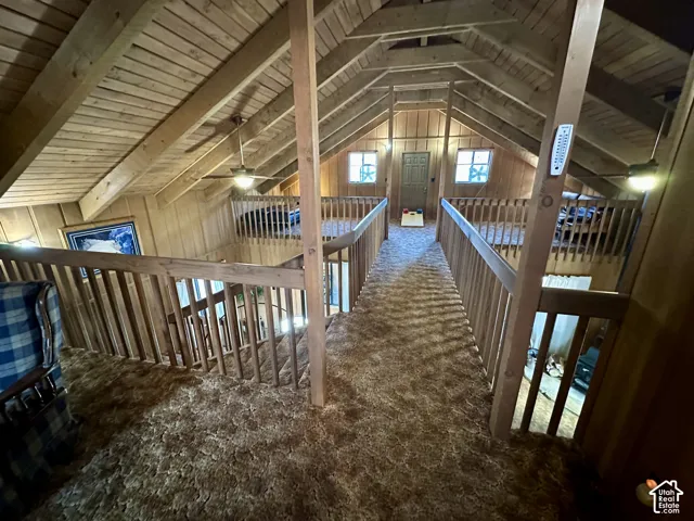Vaulted wood-paneled ceiling, exposed wood beams, wood paneling, wood railing, and ceiling fans