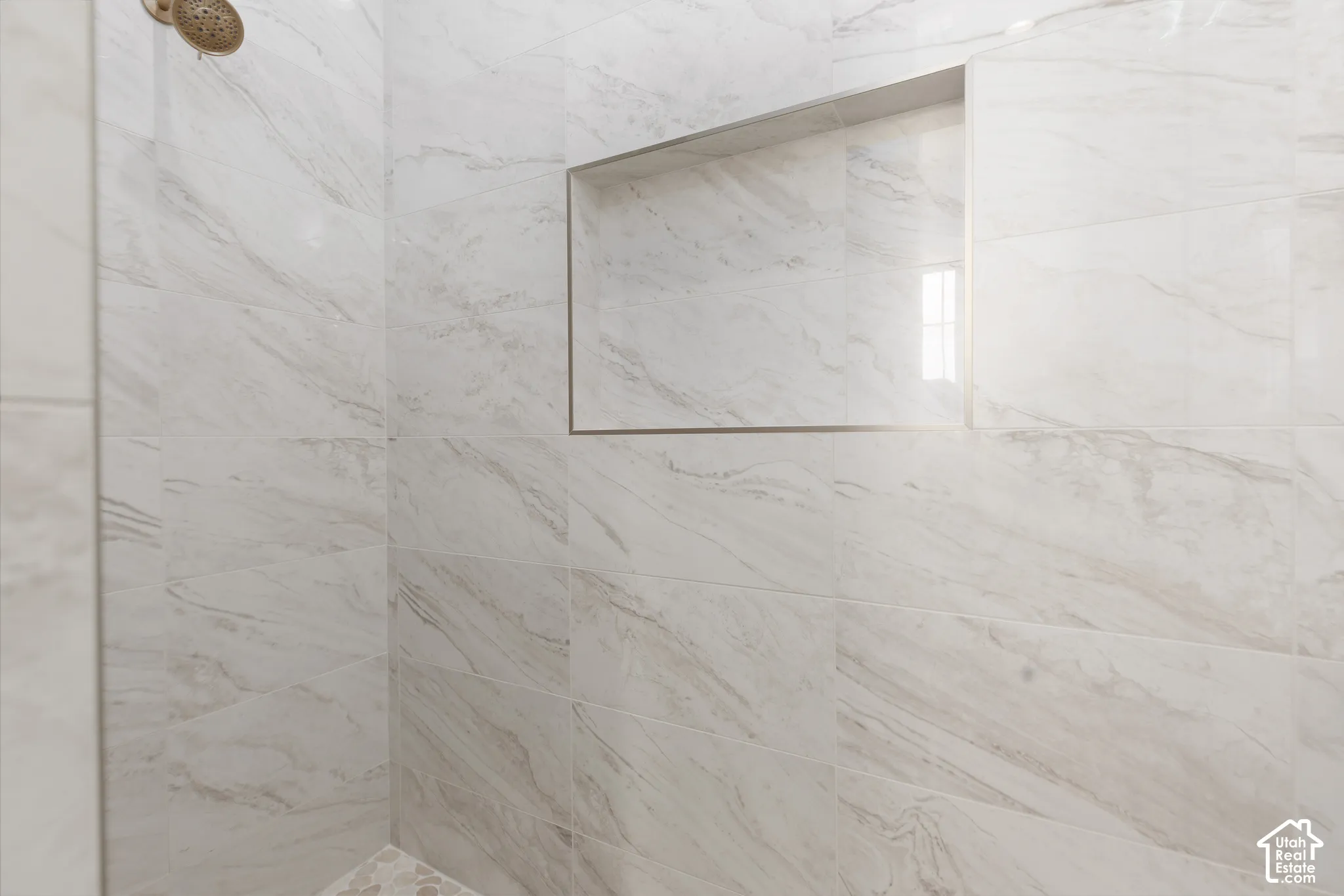 Shower featuring a built-in niche, white tile with subtle veining, and a bronze-finish showerhead