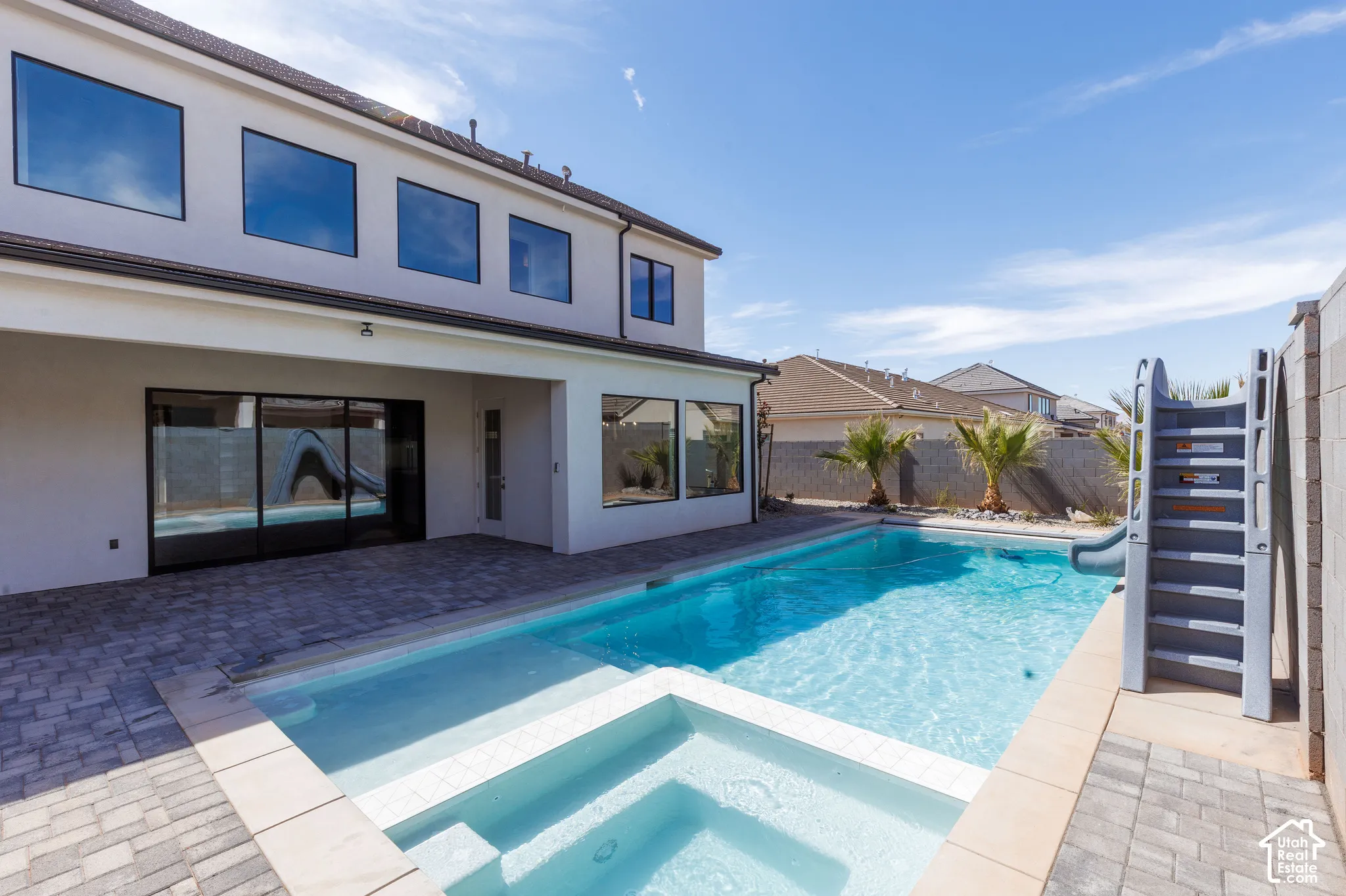 Expansive backyard with a rectangular pool, integrated spa, and paver patio