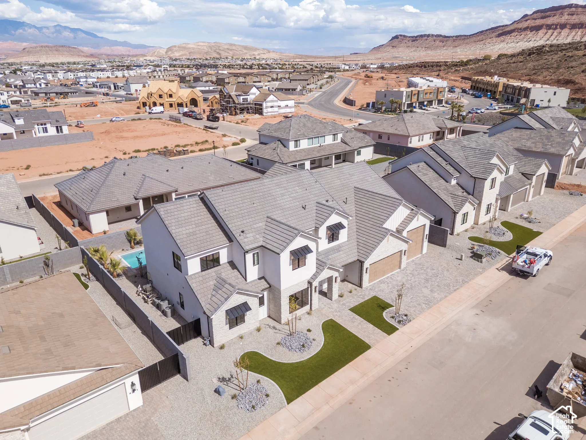Contemporary architecture with a light-toned exterior, multiple gabled rooflines, two attached garages, and a paver driveway
