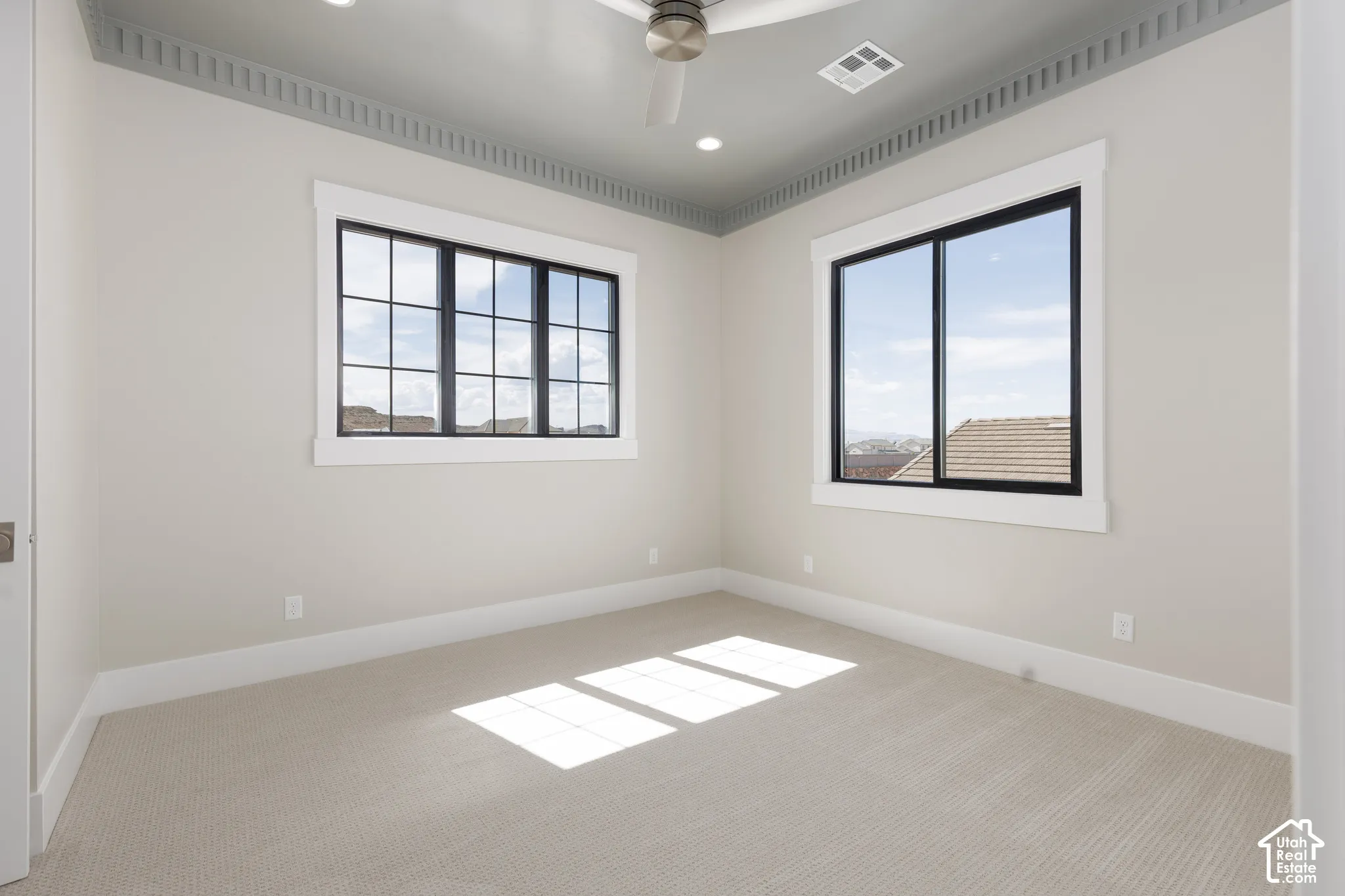 Carpeted flooring, two large windows with black frames, detailed crown molding, recessed lighting, and a ceiling fan