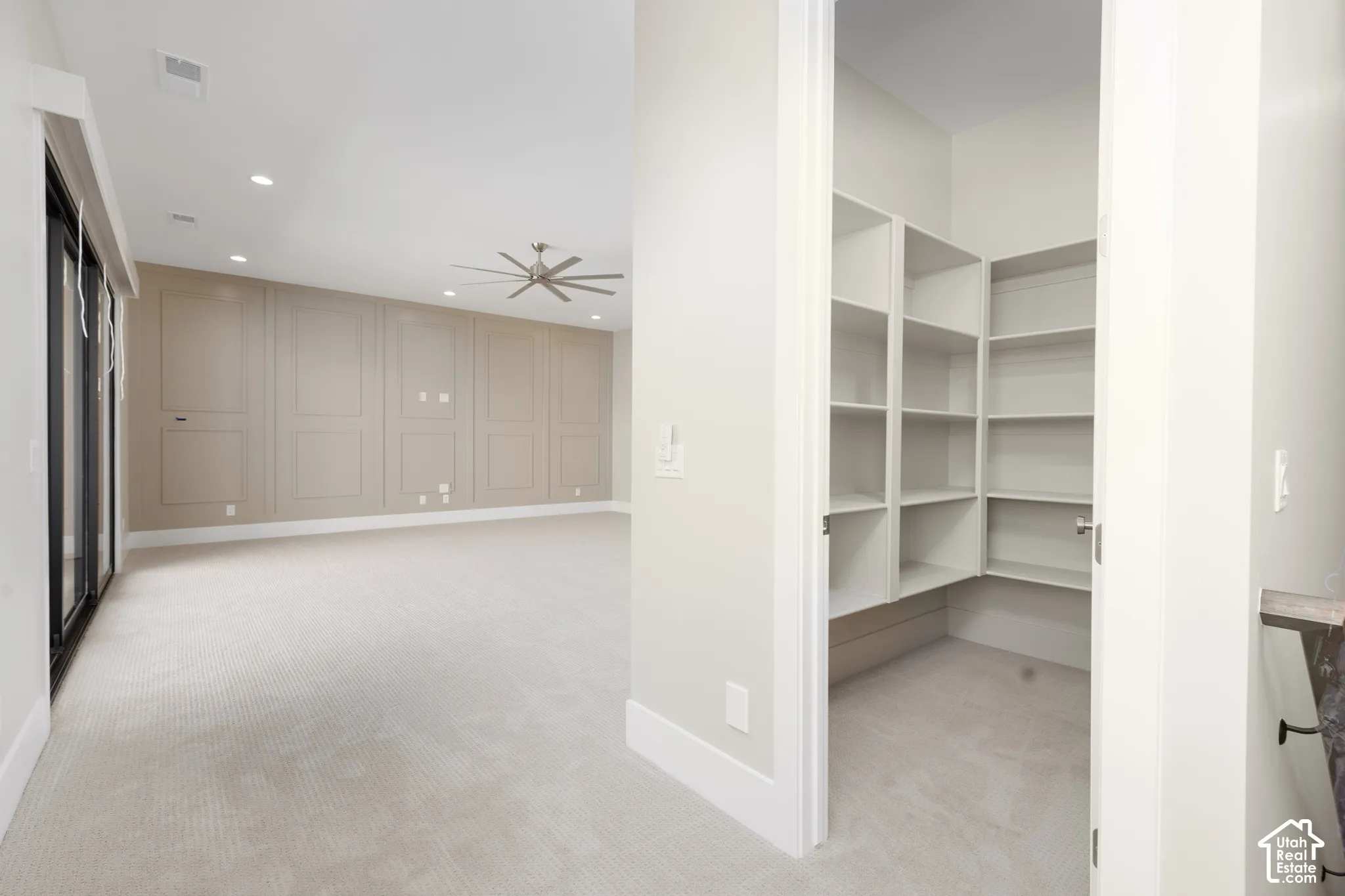 Built-in shelving, recessed lighting, ceiling fan, accent paneling, and wide baseboards