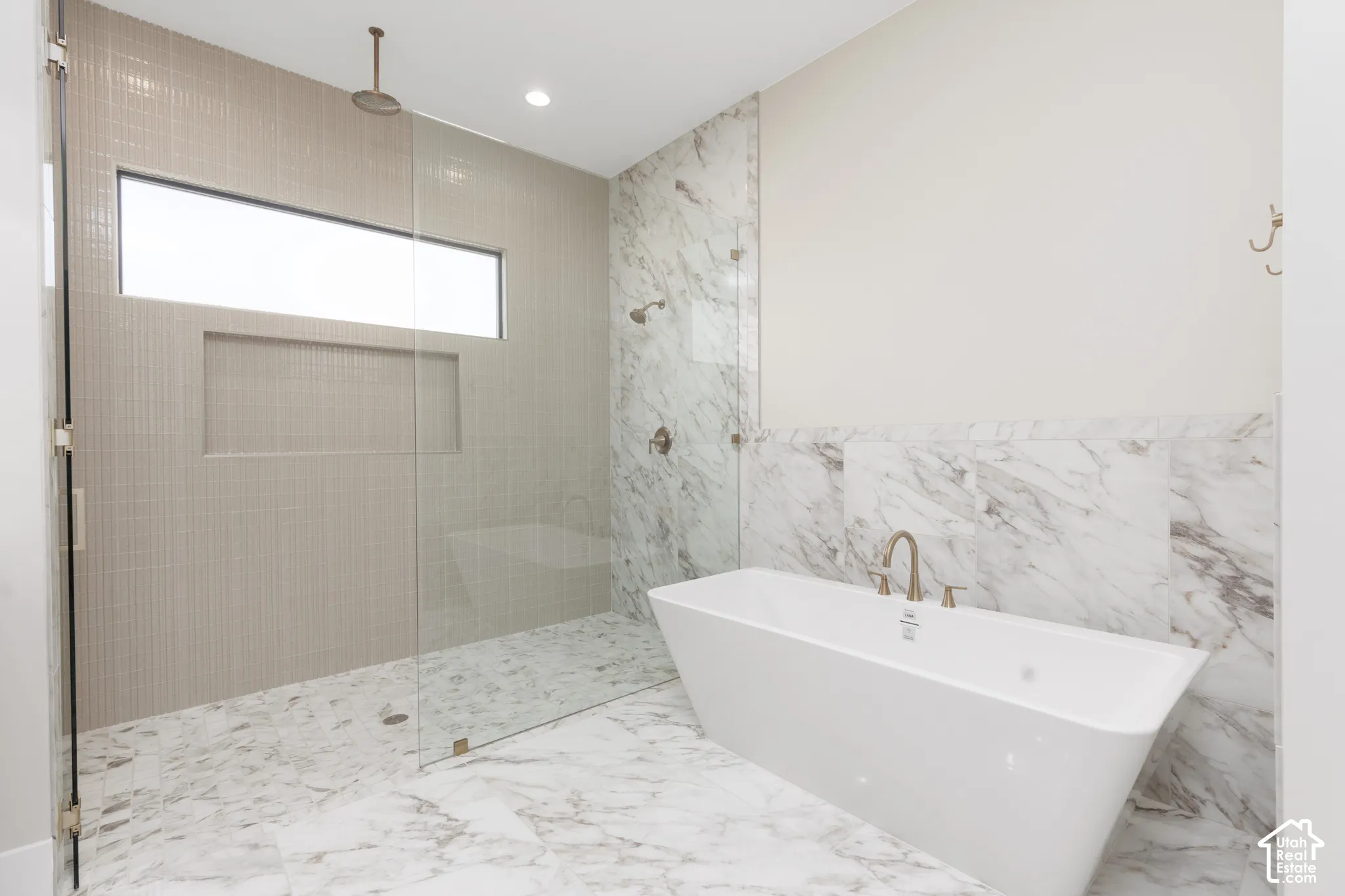 Freestanding soaking tub with a wall-mounted faucet, glass-enclosed shower with a rainfall shower head, and full tile flooring