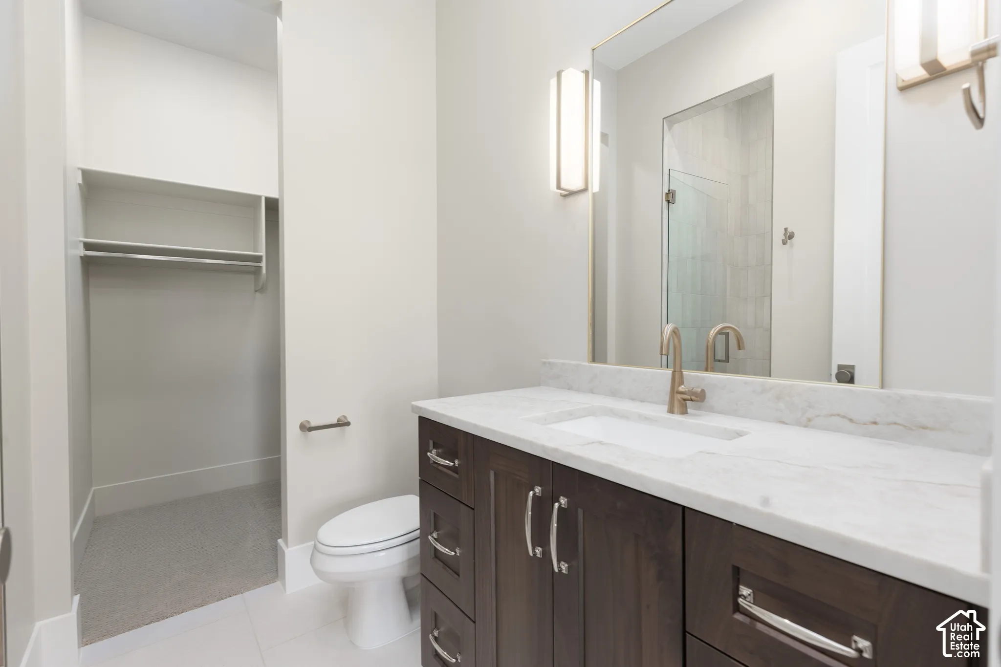 Dark wood-finish vanity with drawer storage, undermount sink, and light-toned countertop