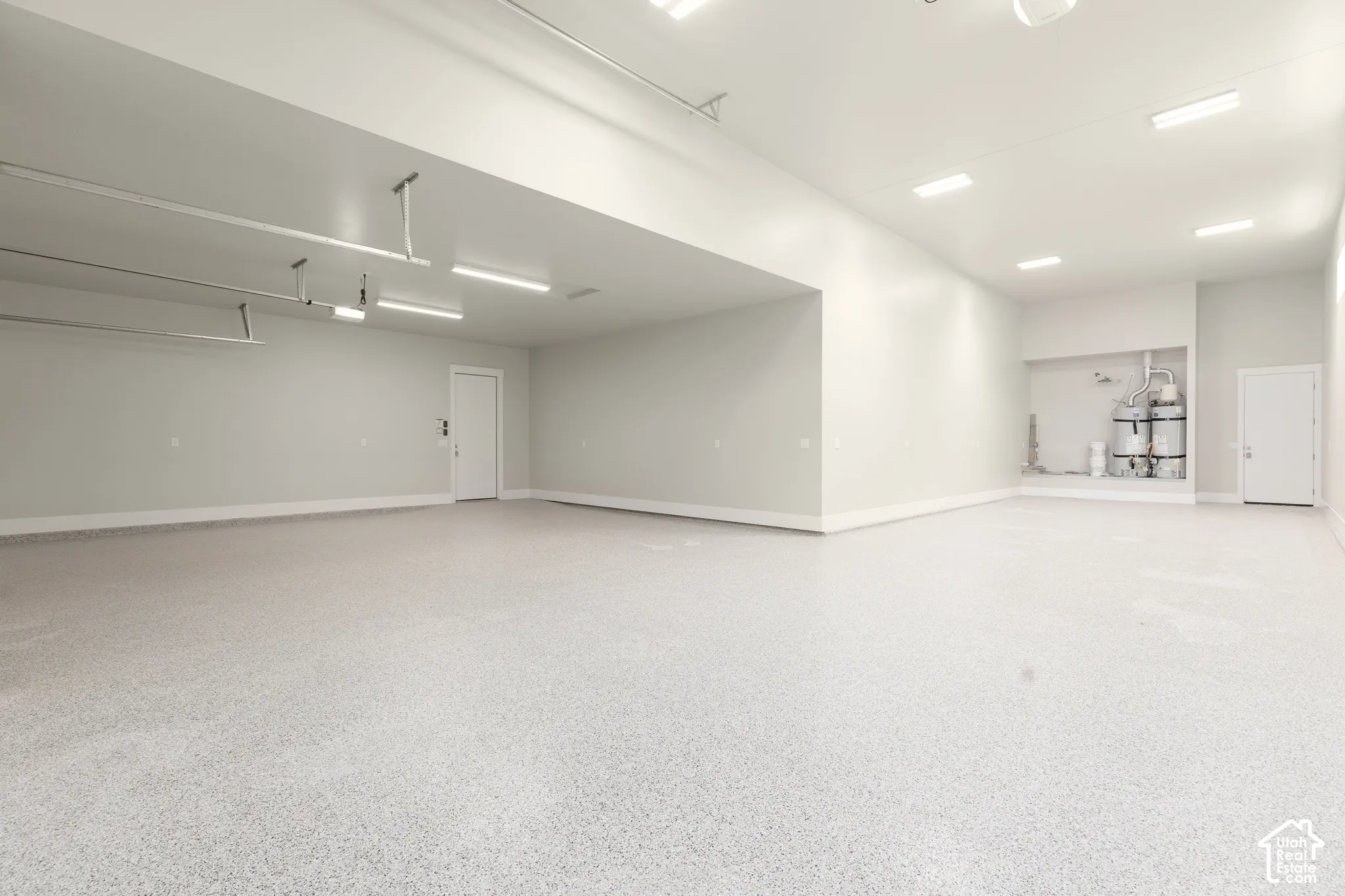 Expansive garage with durable epoxy flooring, overhead lighting, and white walls