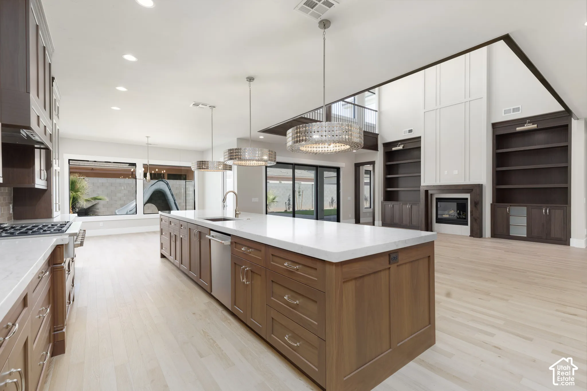 Spacious open-concept living area featuring a kitchen island with sink, integrated dishwasher, and pendant lighting