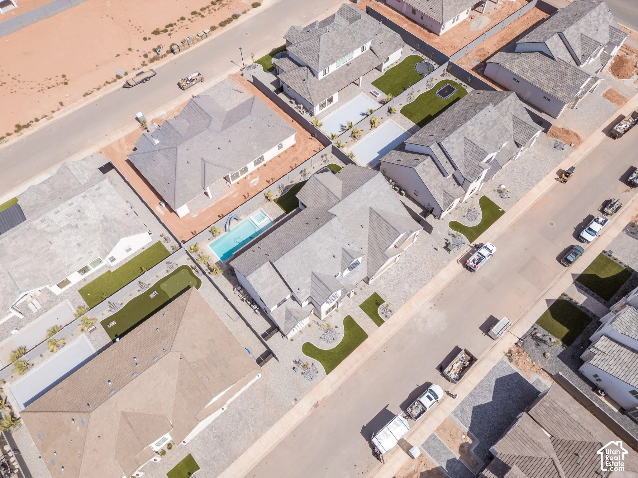 Gable roof design, paved driveways, well-maintained artificial turf, mature landscaping, and a rectangular swimming pool