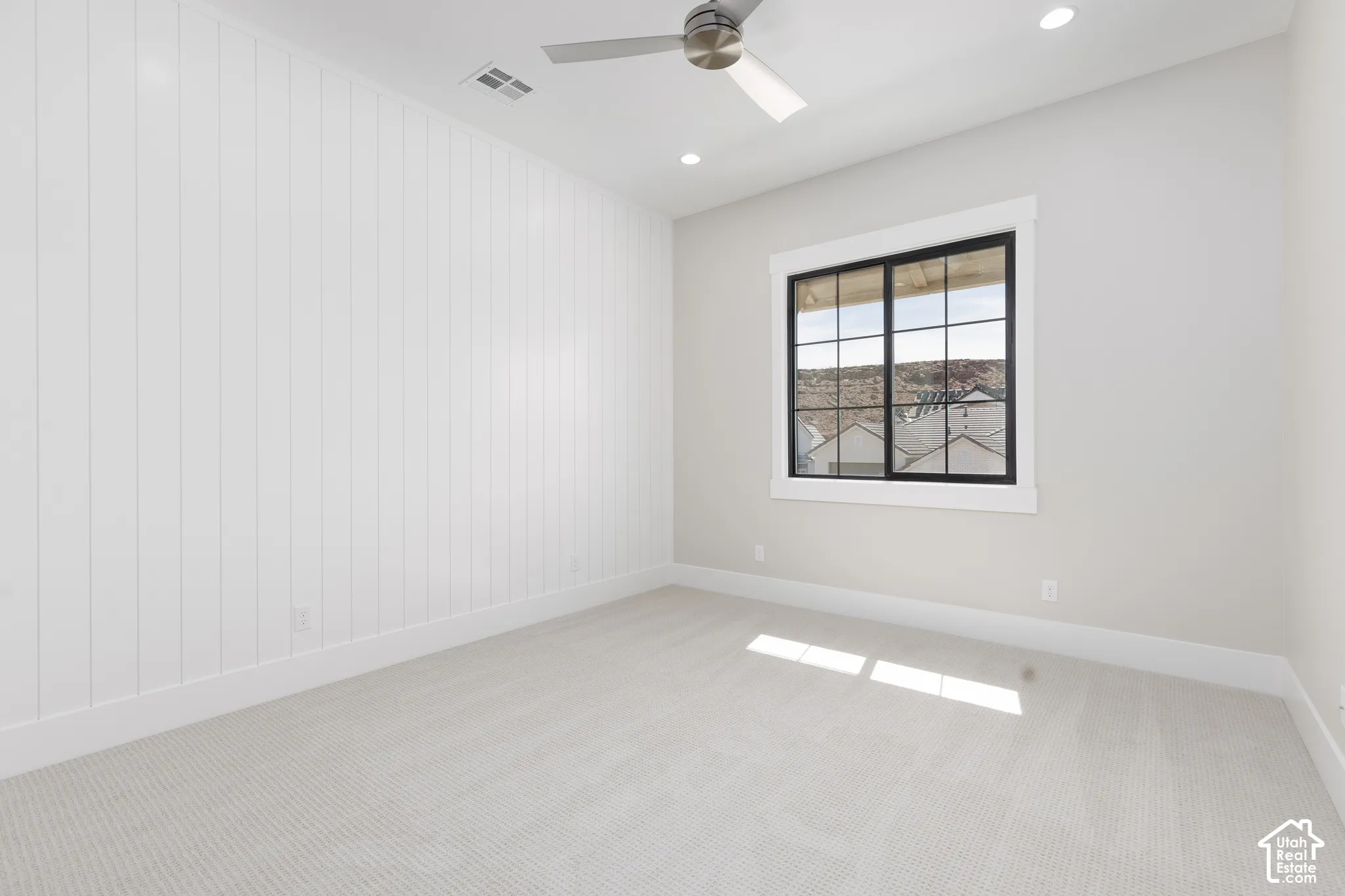 Carpeted room featuring a ceiling fan, recessed lighting, a window with black framing, and a shiplap accent wall
