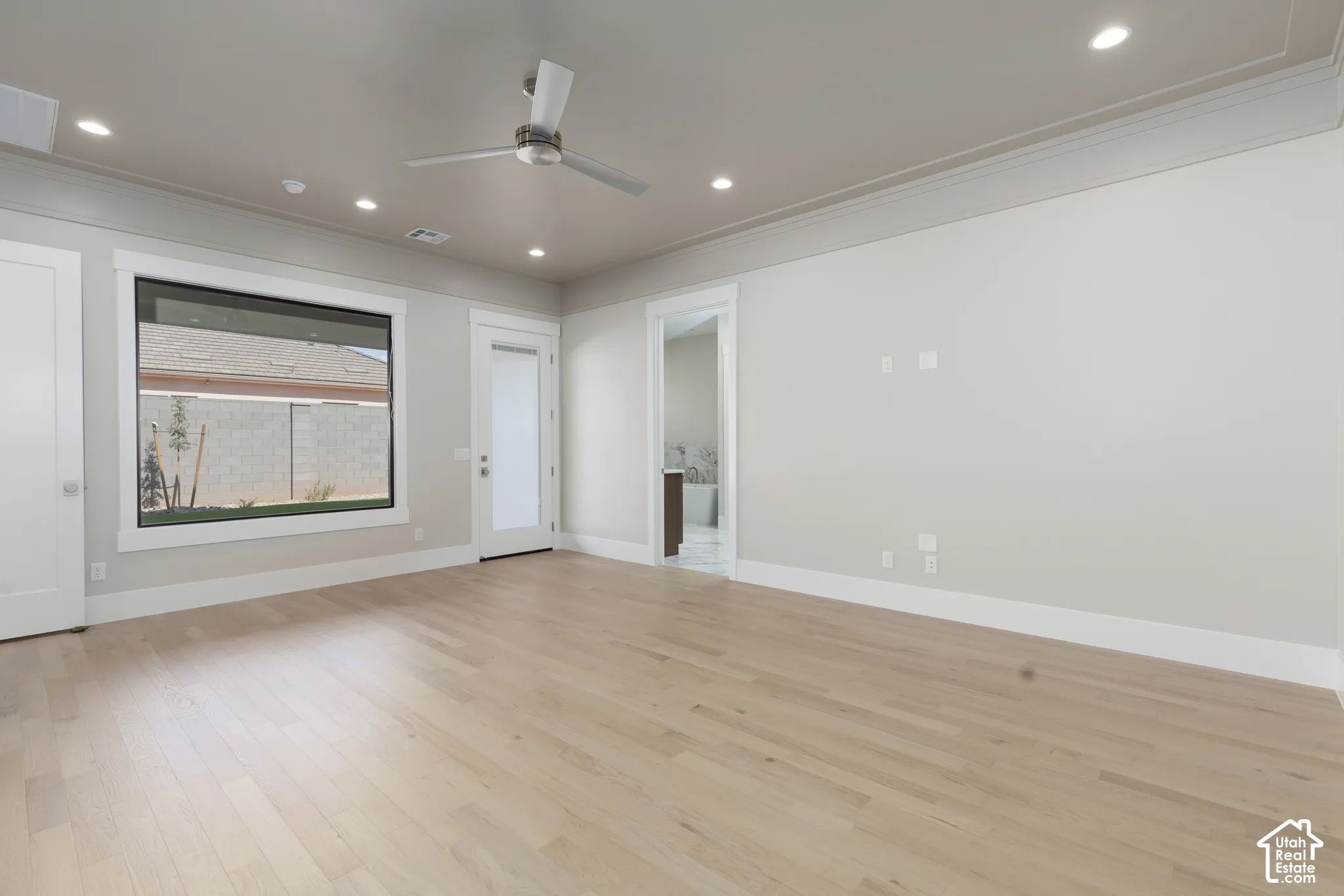 Light wood-finish flooring with recessed lighting and a ceiling fan