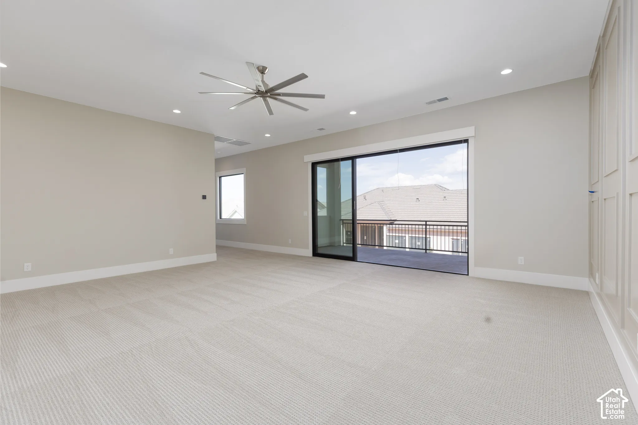 Recessed lighting, ceiling fan, sliding glass door, private balcony with metal railing, panel accent wall