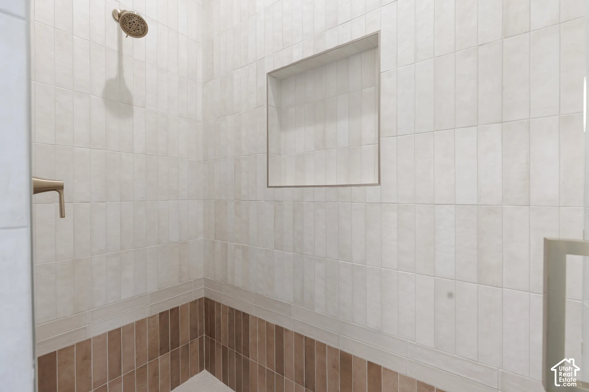Tiled shower with a built-in niche and a bronze-finish shower head