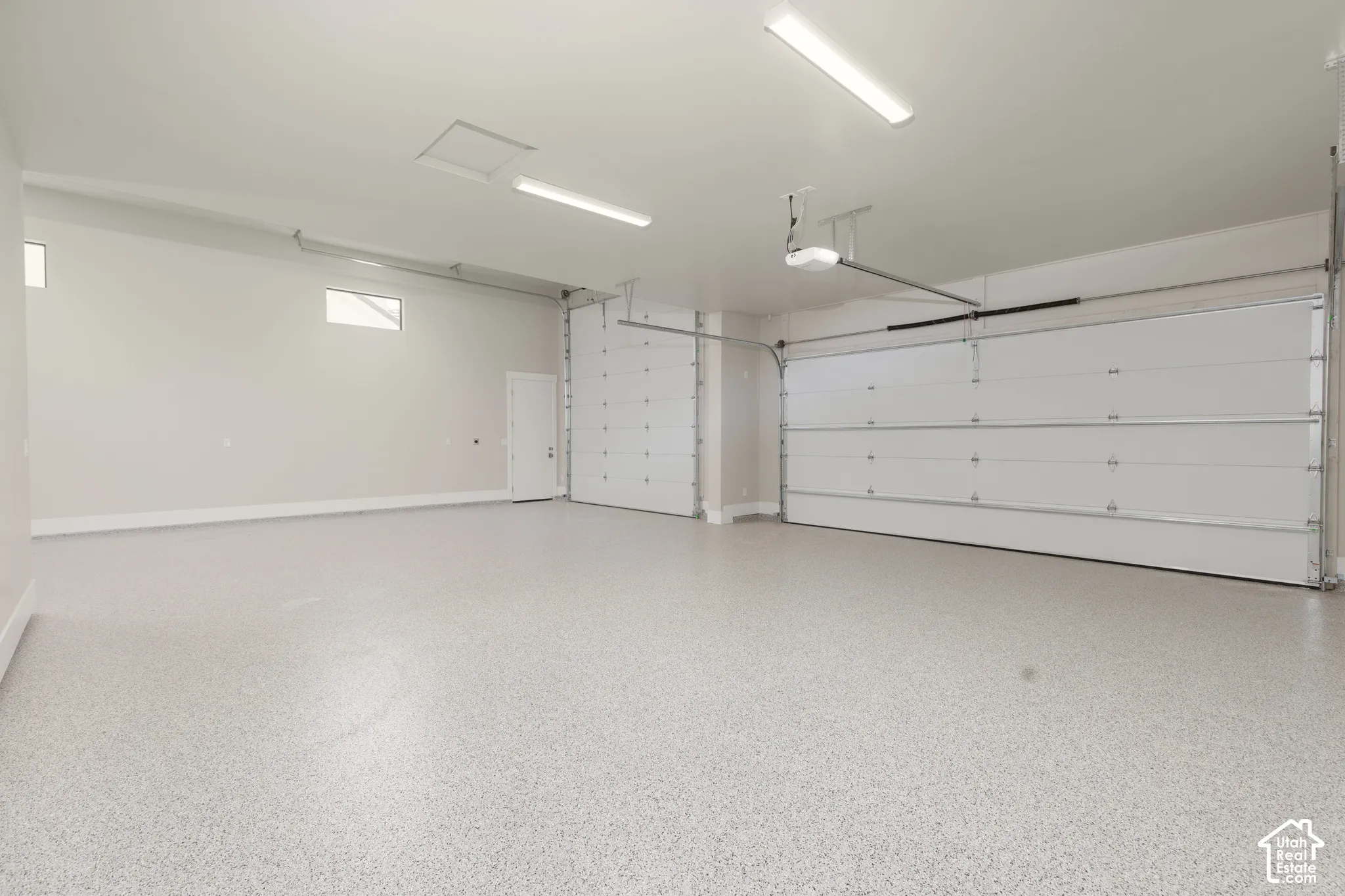 Spacious garage with two overhead doors, epoxy flooring, and ample overhead lighting