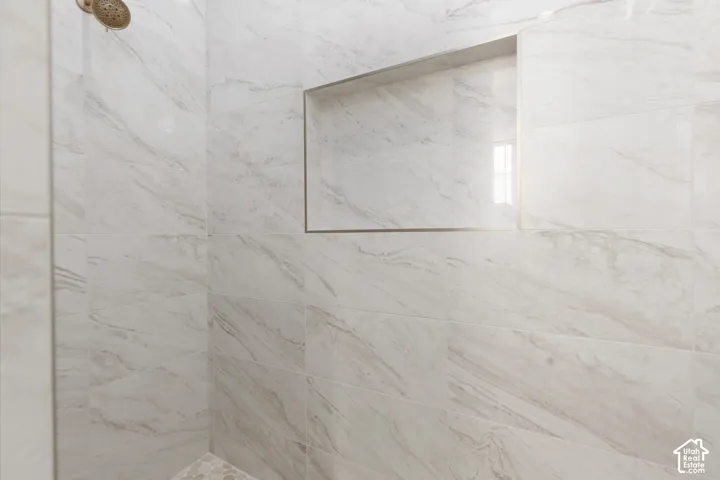 Shower featuring a built-in niche, white tile with subtle veining, and a bronze-finish showerhead