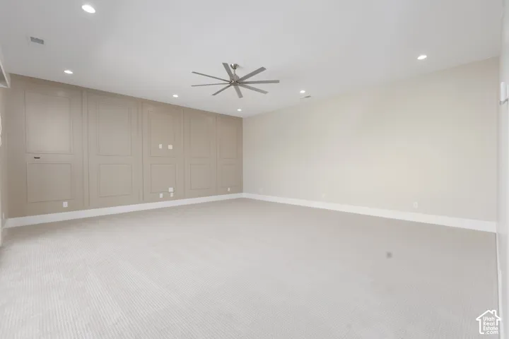 Recessed lighting, ceiling fan, accent wall with panel molding, light-toned carpeting, and crisp white trim