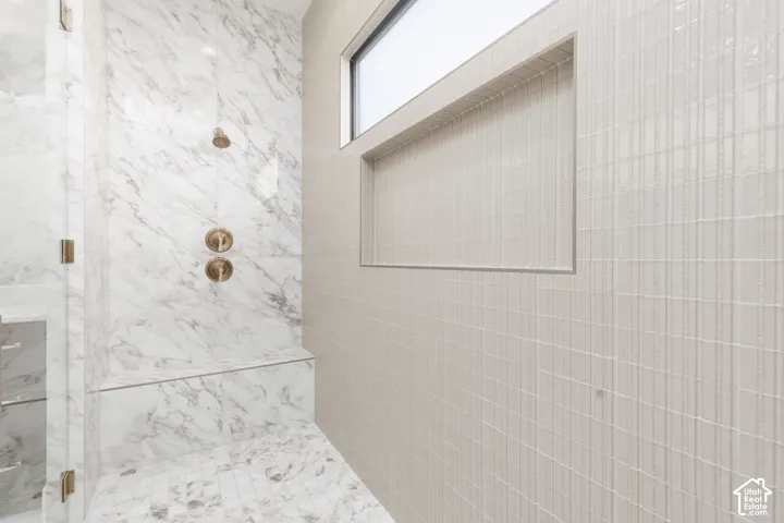 Walk-in shower with marble-finish tiling, integrated bench, and bronze-finish fixtures