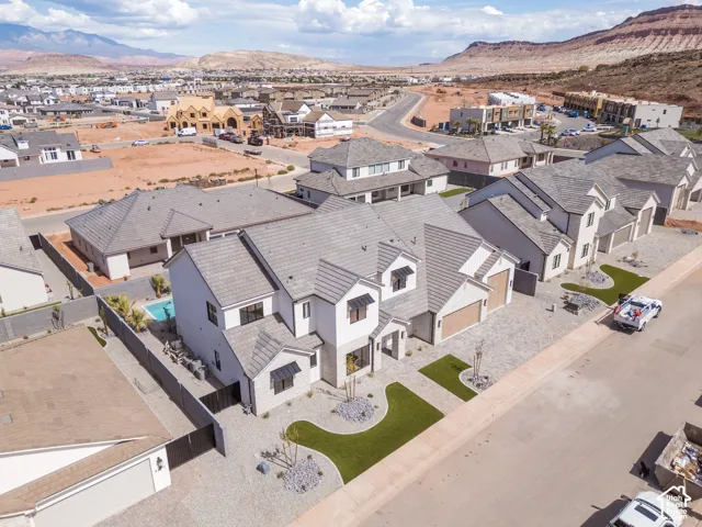 Contemporary architecture with a light-toned exterior, multiple gabled rooflines, two attached garages, and a paver driveway